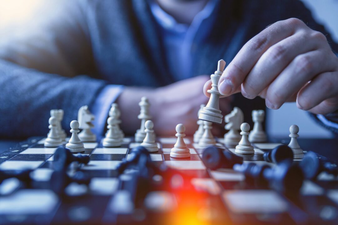 Close up of a man moving a chess piece on a chess board.