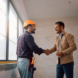 Happy manual worker greeting his client at construction site