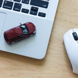 Car Model On Notebook And Mouse On Wooden Desk