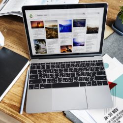 Person working on a laptop creating blog content and managing social media marketing
